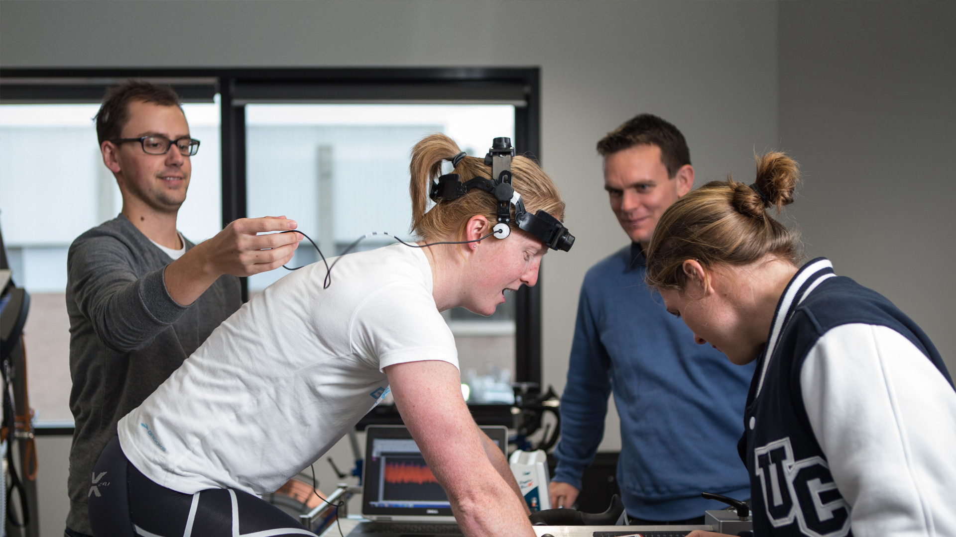 Photo of students working with athlete on static exercise bicycle